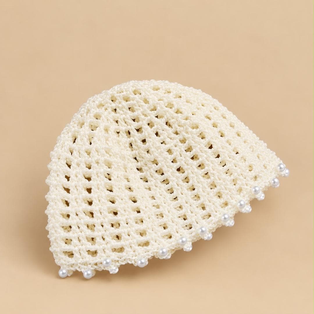 Bonnet crocheté ajouré ivoire, bordé de petites perles nacrées.