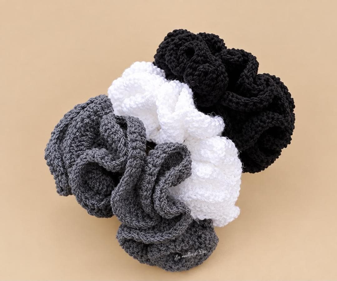 Trois chouchous crochetés à volants : gris, blanc et noir.