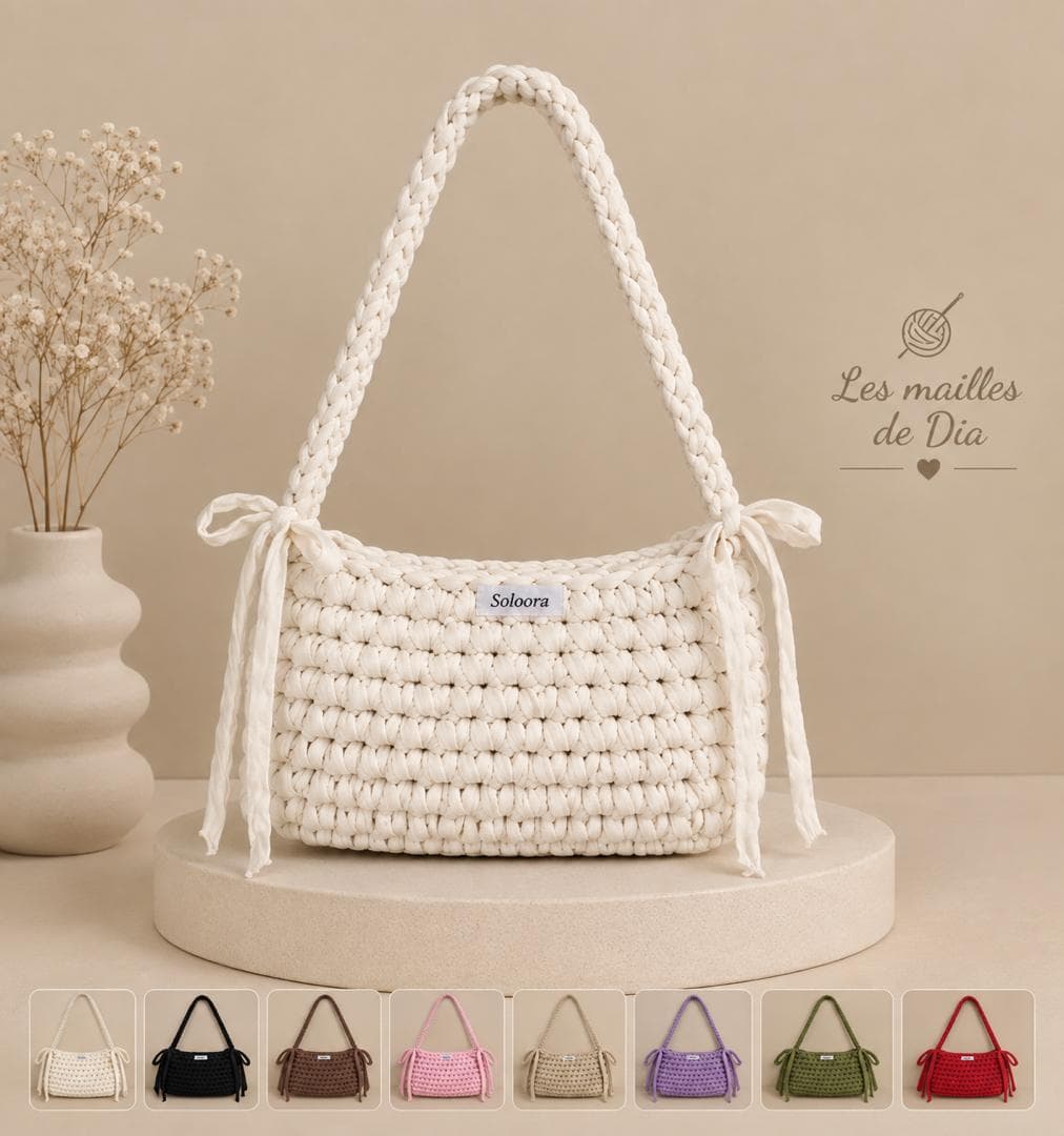 Sac d’épaule crocheté crème à anse tressée, noué sur les côtés, présenté avec des déclinaisons de couleurs.